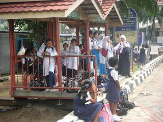 Kinderen in schooluniform bij het busstation